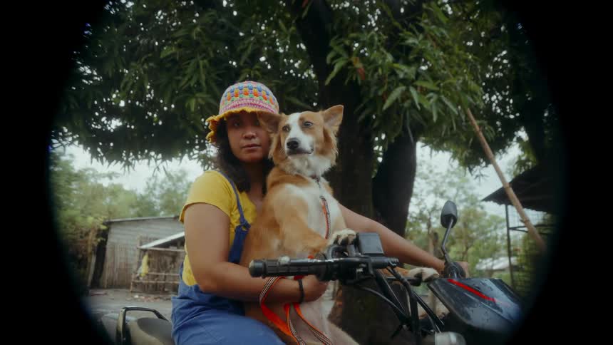 A young Asian woman on motorbike together with her dog