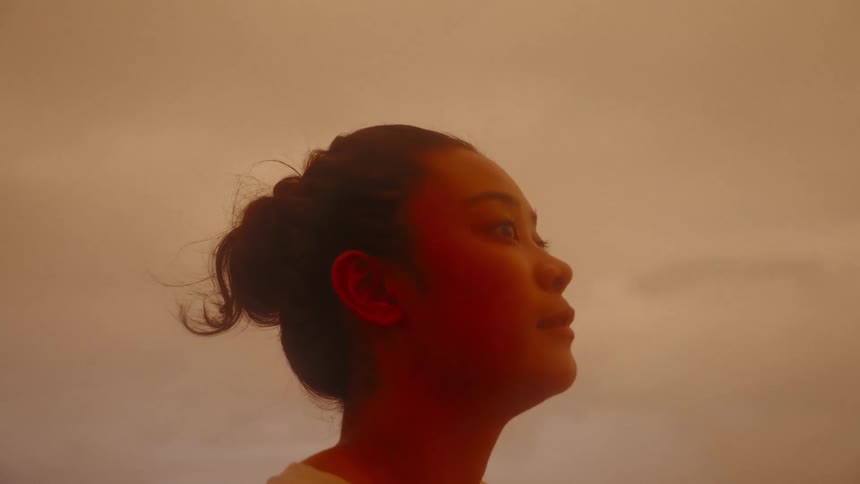 Portrait of a young Asian woman in an open environment on cloudy day with wind