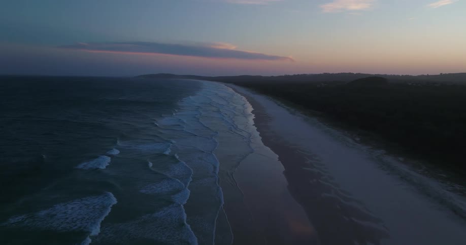Multiple waves wash upon the sandy beach that lines the coast