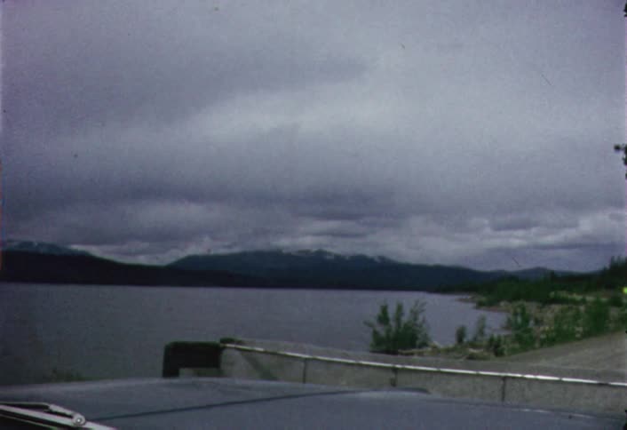 A vehicle drives on a lakeside road