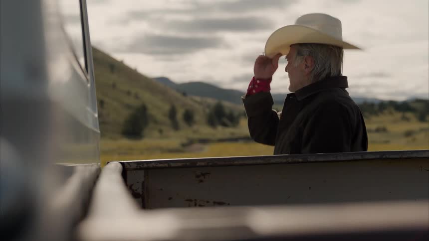 Elderly man taking off his hat arranging his hair and me putting it back on while outdoors next to mountains on a cloudy day