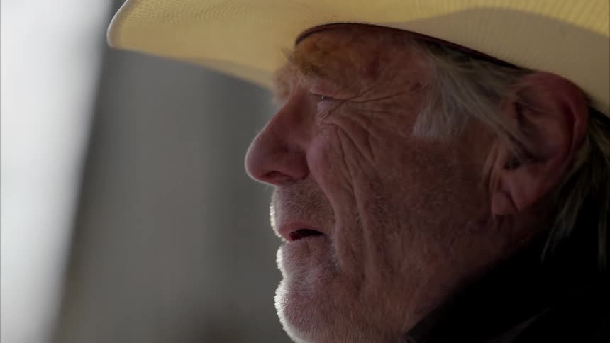 A sad old cowboy stares into the distance almost crying