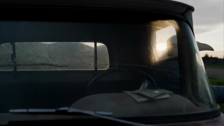 An elderly man wearing a cowboy hat sits in a car and then gets out of it