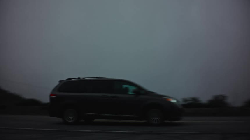 Cars drive down a road under stormy looking clouds