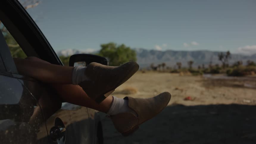 A womans legs sticking out of the front window of a vehicle