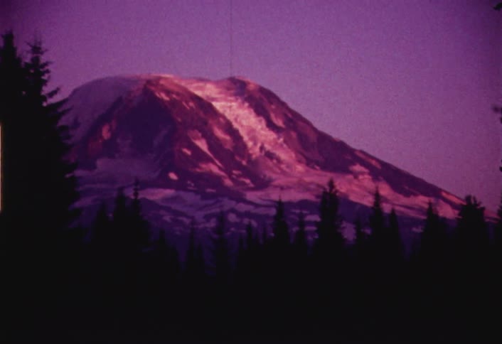 Zooming view of a mountain with trees in the foreground on a clear day