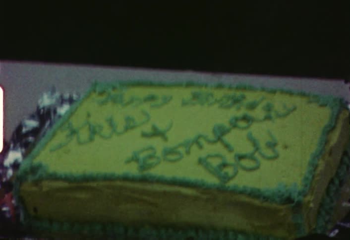 A card with a cat on it is placed on a birthday cake