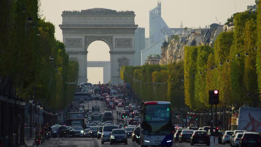 The arc de triomphe stands at the end of a bustling avenue