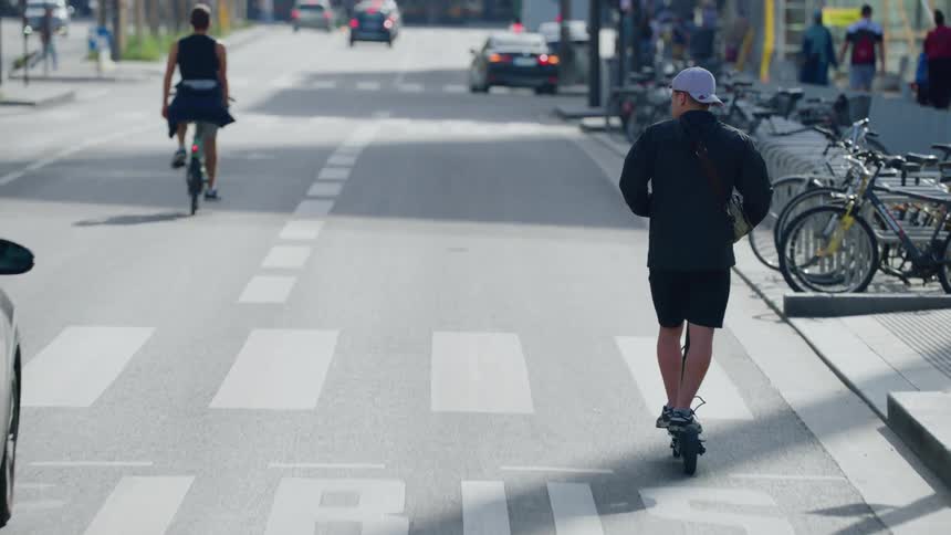 A clip of two people skating and cycling on the street