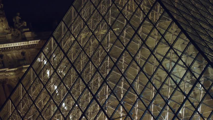 A large pyramid of glass is in front of the building
