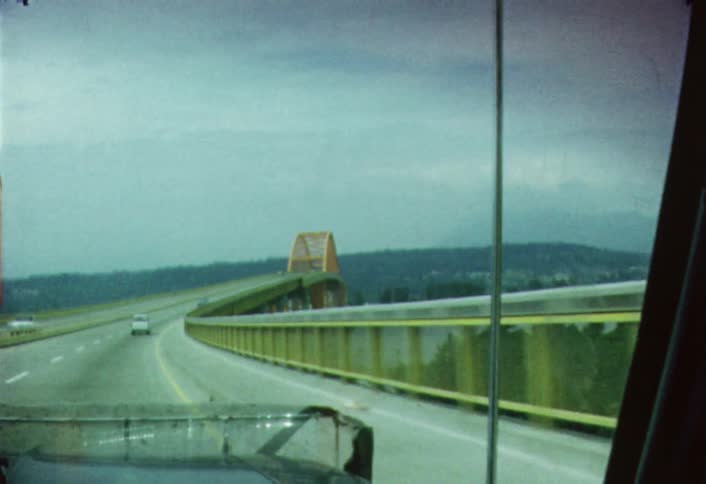 Moving view of traffic as the vehicle is heading towards a bridge  that spans a large river