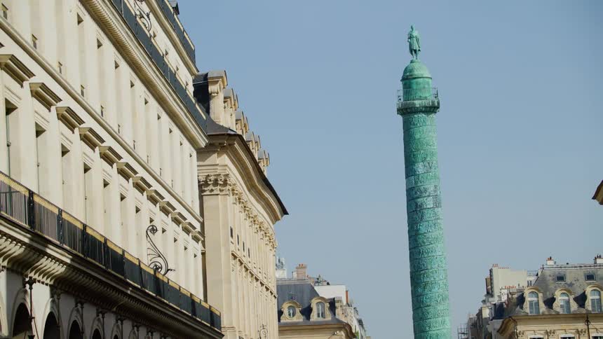 Blue column topped with sculpture stands between apartment buildings