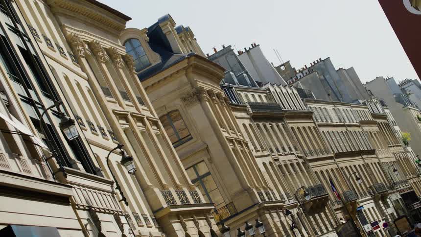 A street with several buildings of similar architecture and several balconies in the windows