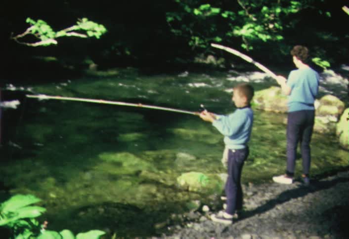 A boy and a woman are fishing in a river