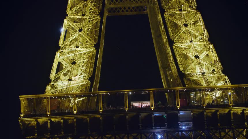 The eiffel tower is illuminated at night with blue flashing lights