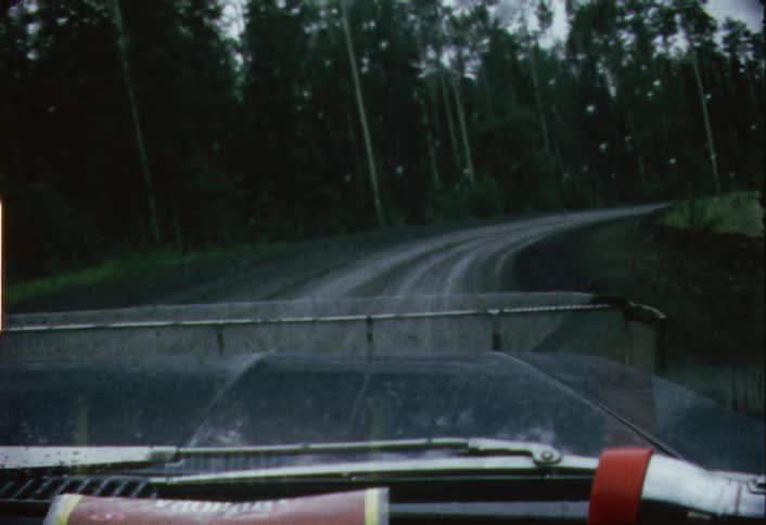 Car driving down a dirt road on cloudy evening