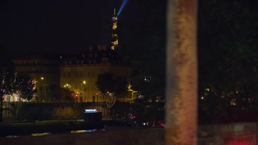 People walk next to a river near the eiffel tower