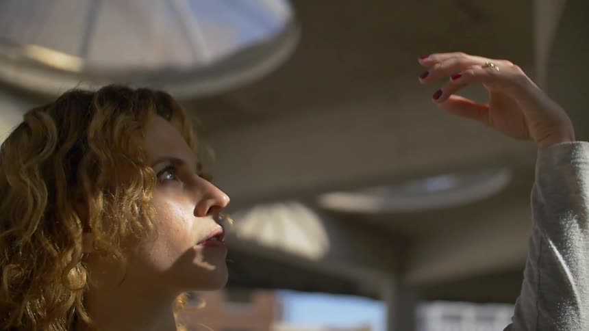 A woman holds her hand op into the light