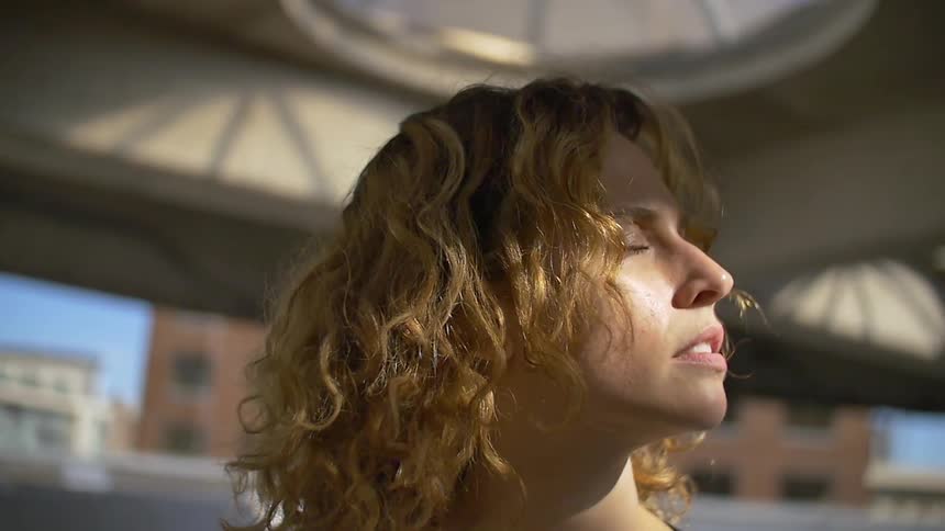 A woman has her eyes closed and her face is turned to the sun