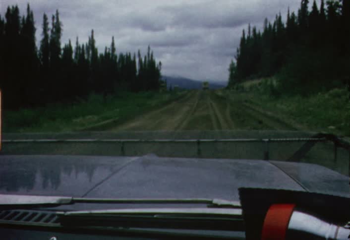 Car driving down a dirt road on cloudy evening