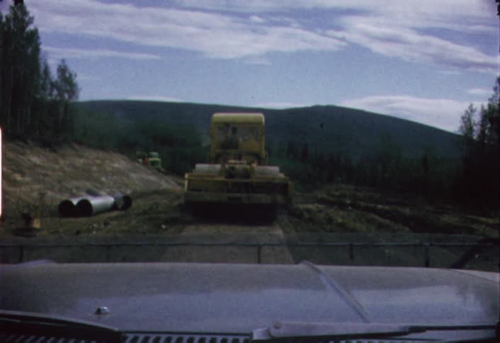 Heavy equipment vehicle  as seen through the windshield of a moving vehicle following behind it