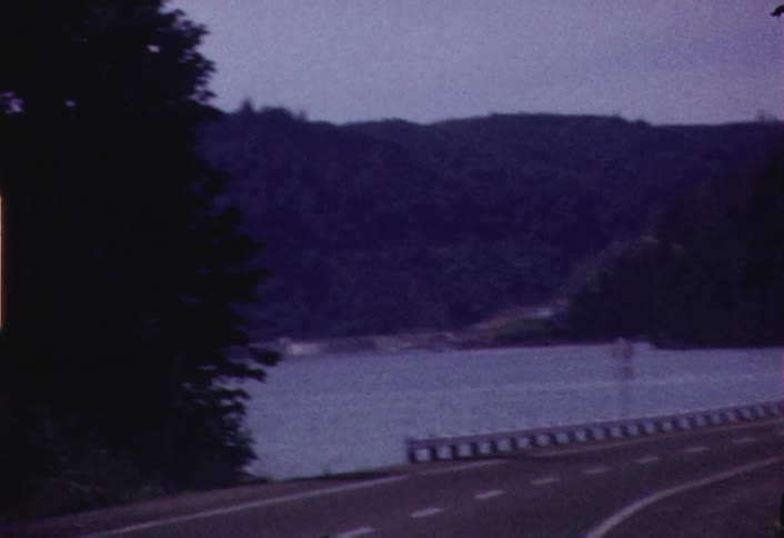 Shaky view  of a lake and hillside from a moving car