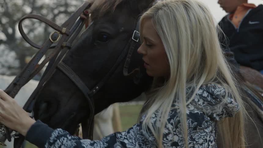 A woman is putting a bridle on a horse