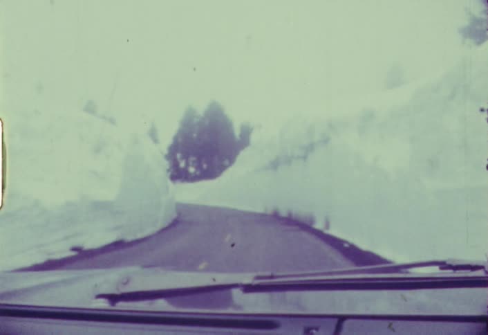 An old film of someone driving a vehicle down a road