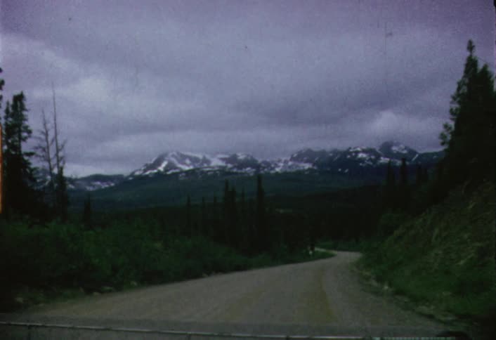 A dirt road leads to a snow covered mountain ahead