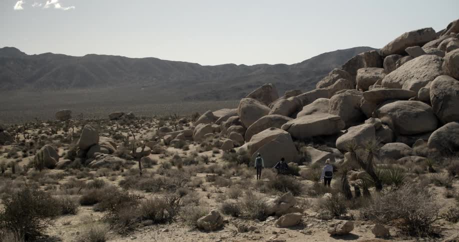 Hikers walk near large boulders in the desert