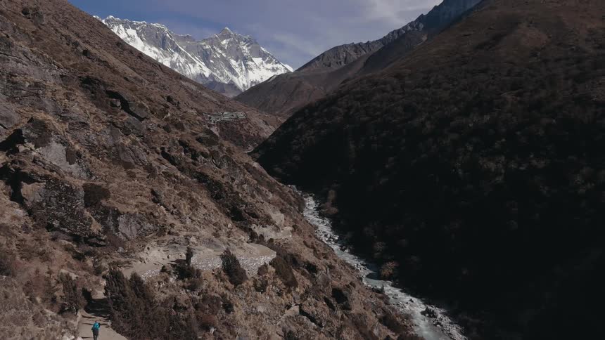 Natural landscape of ruins and snowy mountains with a side river on a blue sky day