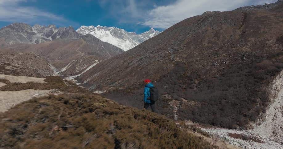 Backpacker hikes across top of hill overlooking stream on a cloudy day