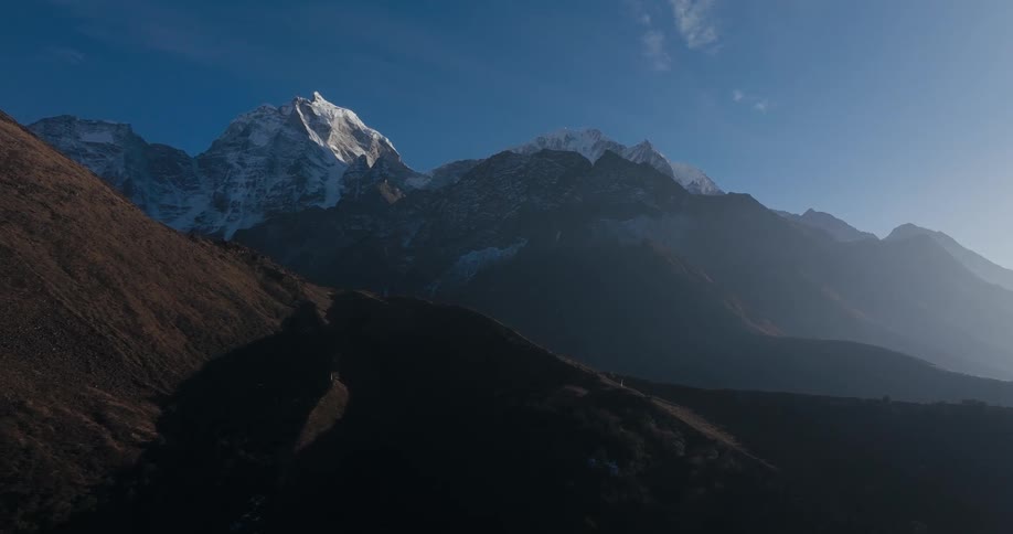 A mountainous region with the highest mountain covered in snow at the top and there is strong sunlight coming from the right