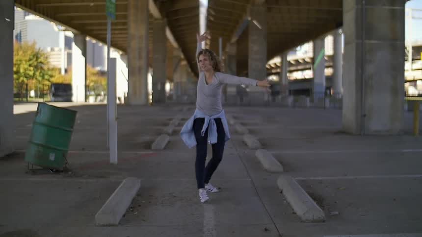 A woman is dancing under an overpass