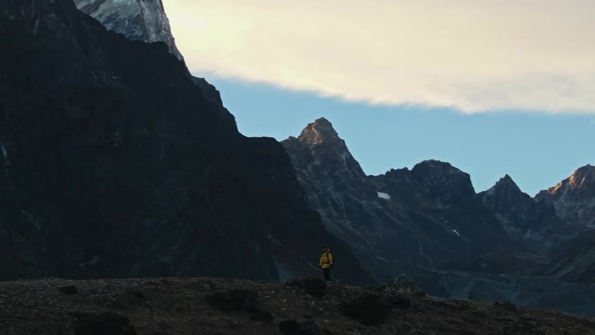 Man hiking on a hill surrounded by mountains in winter during the day