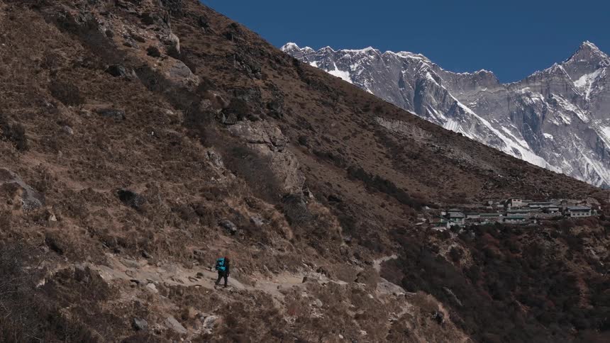 A person walking through a mountain valley towards a village