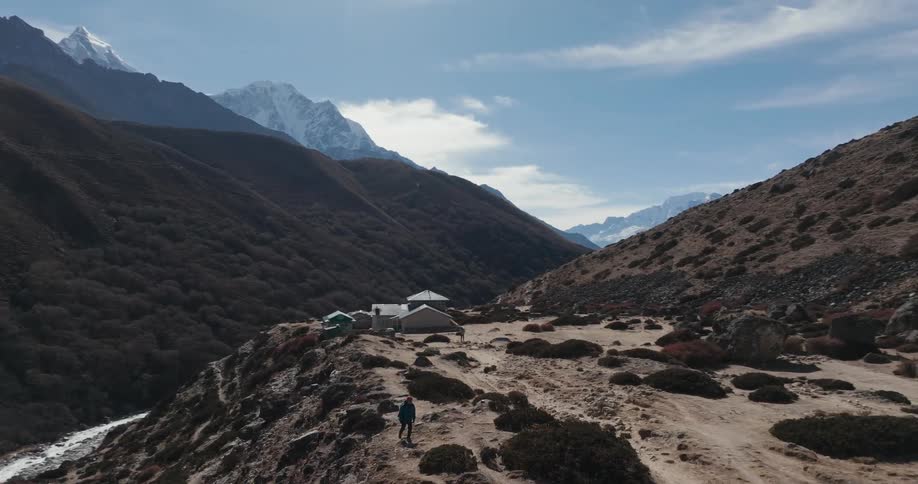 Person walking on a hill surrounded by mountains and blue sky indians with clouds
