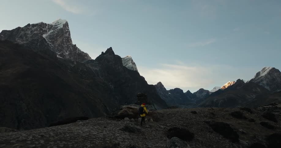 Person hiking on a hill surrounded by mountain ranges in daylight