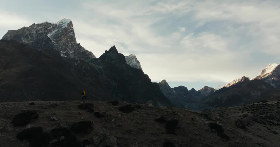 Person walking on a hill hated by mountain ranges in winter
