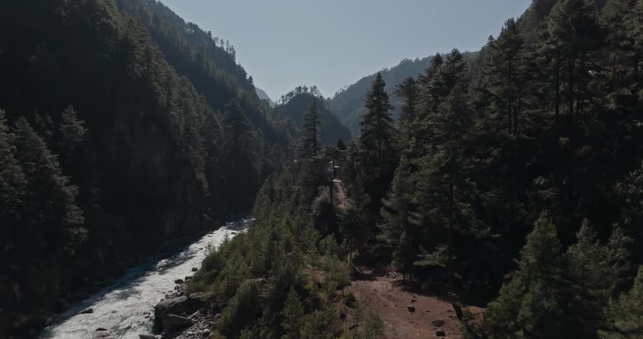 Wooden suspension bridge crossing a river and connecting two mountains and forests