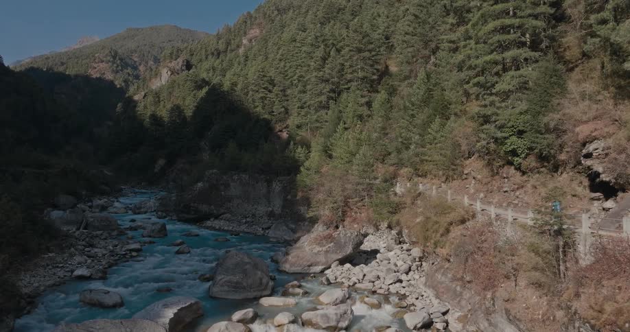Backpacker hikes along path paralleling stream between forested mountains