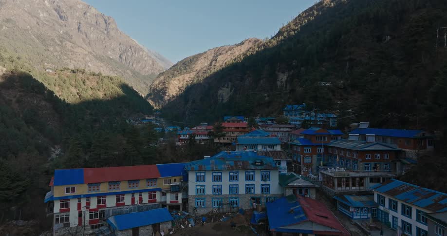Numerous buildings are located within a valley surrounded by tall mountains