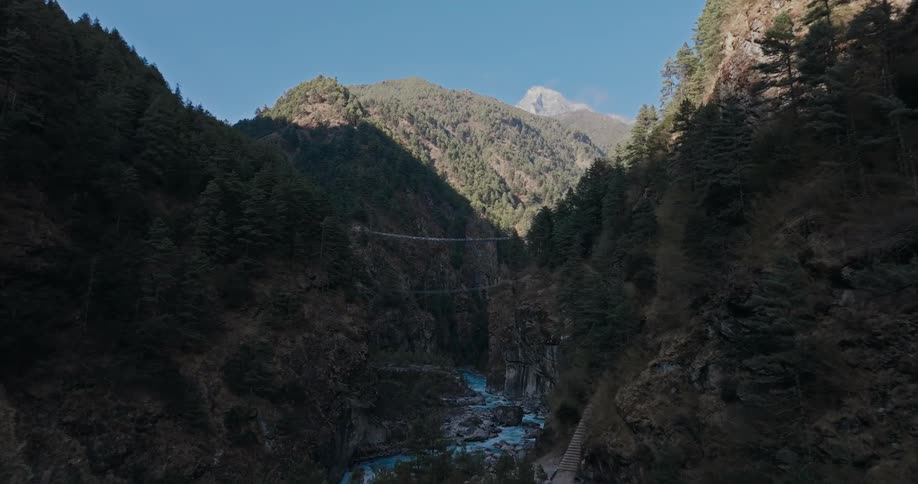 A river flows along the bottom of a forest lined canyon within a mountain range