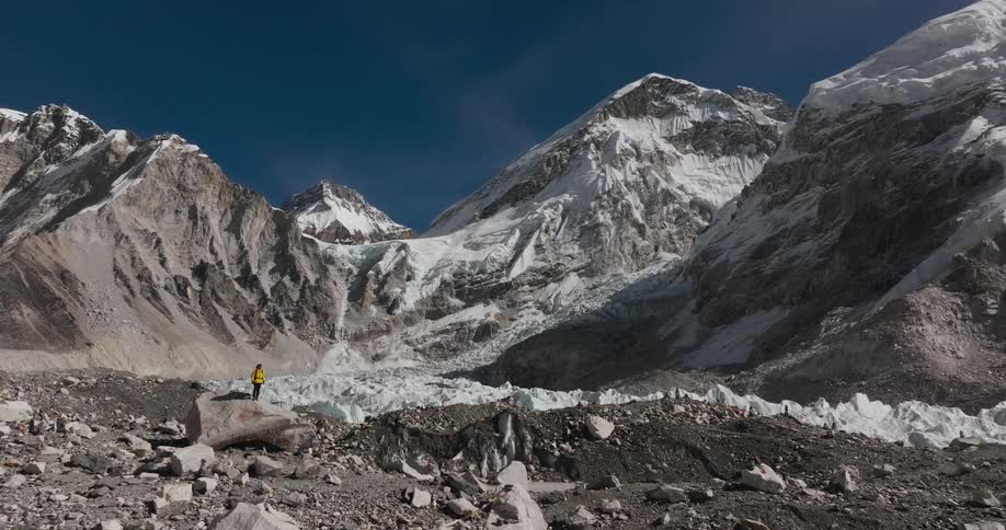 Person on top of a rock observing the landscape of rocky mountains covered by snow