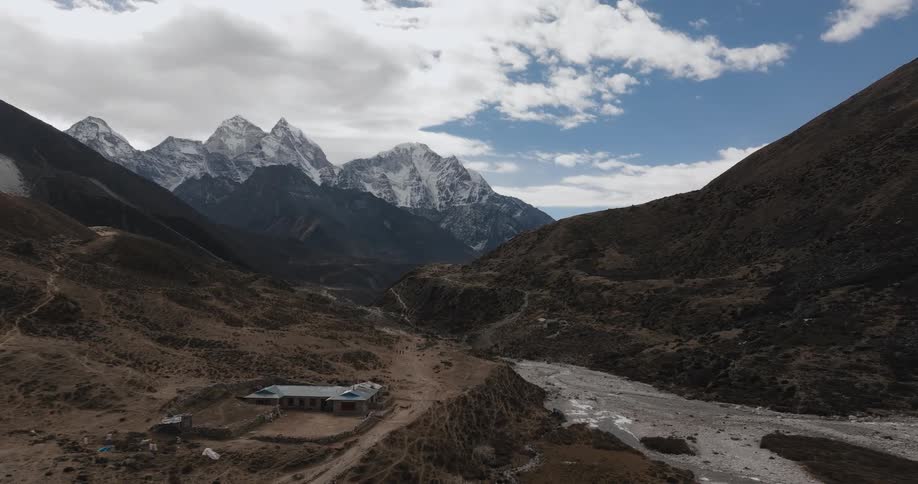 A lone building is built in a remote valley surrounded by mountains