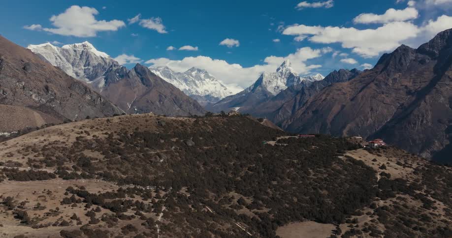 A towering range of mountains surrounds a valley under a cloudy sky
