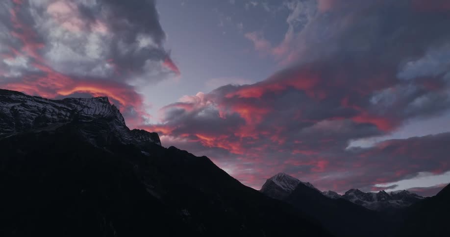 Silhouette landscape of mountains and their peaks covered by snow in a reddish and purple morning sky