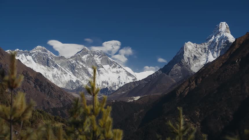 A landscape of a mountainous region and one of them has snow on top