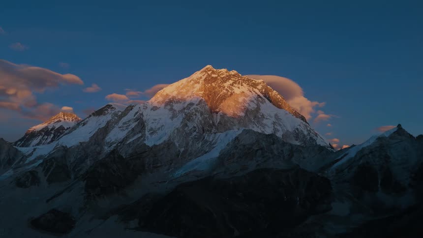 Clouds hover over a high mountain peak