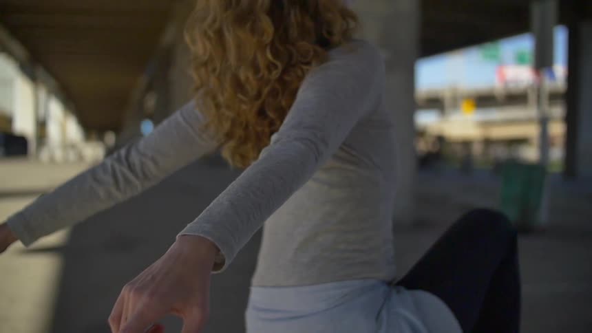 Woman stretching her arms back outside under bridge